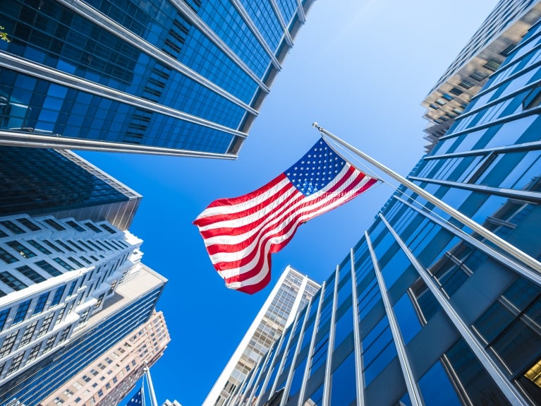 American flag between a city block of tall buildings