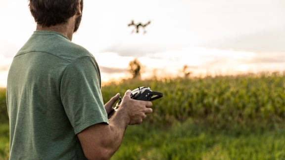 Autonomous & Uncrewed Vehicle Systems image, man flying a drone in a meadow at sunset